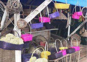 Exibição de cestas em um mercado, com uma variedade de produtos locais e artesanais visíveis nas cestas.