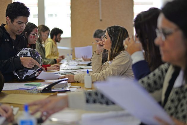 Mesa com alunos realizando inscrição e funcionários da Cdara recebendo os documentos (Foto: Twin Alvarenga)