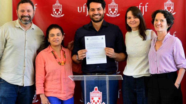 Novo docente do ICH, Max Wendell dos Anjos, ao lado da reitora, Girlene Alves, da pró-reitora de Gestão de Pessoas, Isabela Veiga, do vice-reitor do ICH, Wagner Batella e da chefe do Departamento de Geociências, Clarice Cassab Torres (Foto: Twin Alvarenga/UFJF)