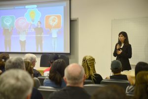 Imagem do evento do CGCO com a gestora palestrando e convidados assistindo.