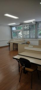 sala com piso laminado, mesas de escritório e janela ao fundo