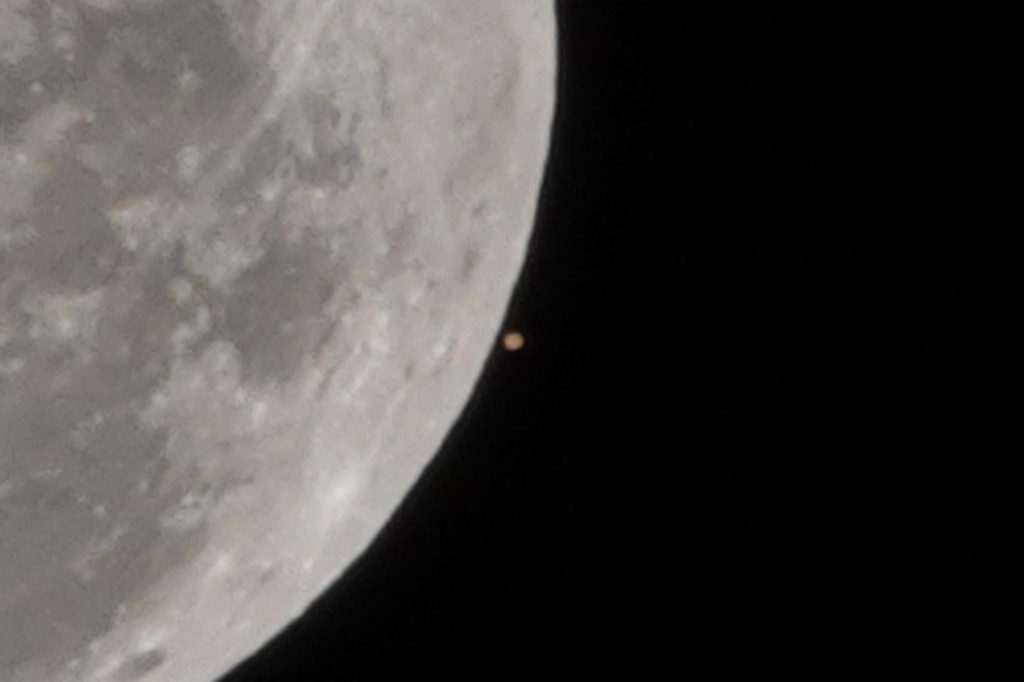 Foto mais próxima da Lua com Marte bem pequeno ao seu lado, prestes a ser ocultado por ela.