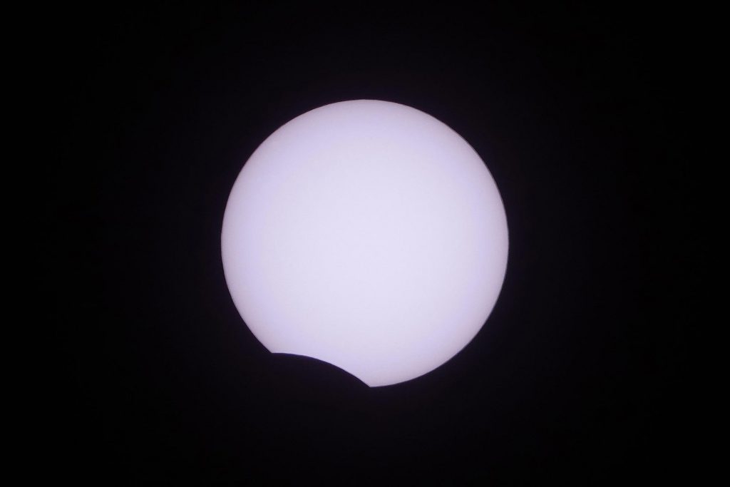 Foto do eclipse solar parcial, com a Lua tampando apenas uma pequena parte do Sol.