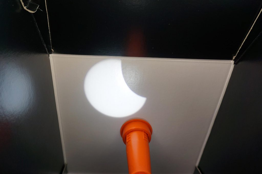 Eclipse solar parcial em seu ponto máximo, observado a partir da projeção com Solarscope. É como uma caixa de papelão, observada por dentro, com uma pequena luneta entrando na caixa, e a imagem do eclipse é refletida por um espelho na face interior, logo acima da luneta.