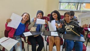 Alunas da Escola Municial Santa Cecília sorrindo e mostrando suas criações dentro da Editora UFJF