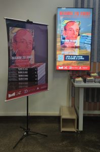 Banner de lan&ccedil;amento do livro do MAMM 20 anos: preserva&ccedil;&atilde;o, pesquisa e difus&atilde;o presente dentro do museu ao lado dos livros disponibilizados.