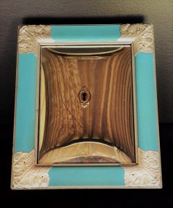 "Janela imunológica", obra da artista Sandra Sato, semelhante a uma moldura azul com uma espécie de madeira com uma fechadura no meio. 