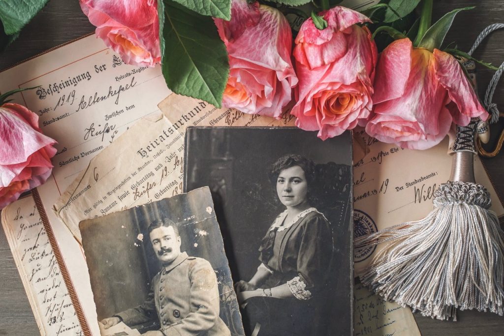 Imagem de papeis antigos, fotos em preto e branco e algumas flores (rosas).